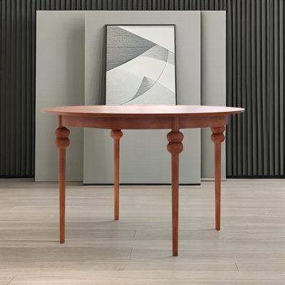 a wooden table sitting on top of a hard wood floor next to a framed painting