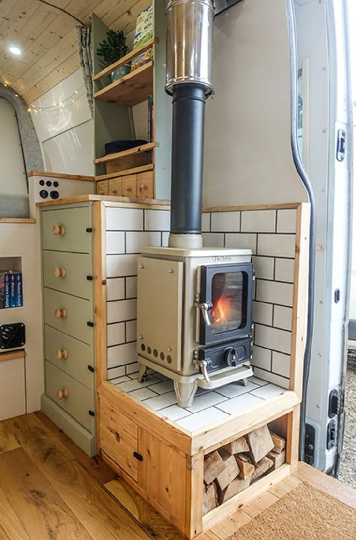 the interior of a small camper with wood burning stove and storage area in it