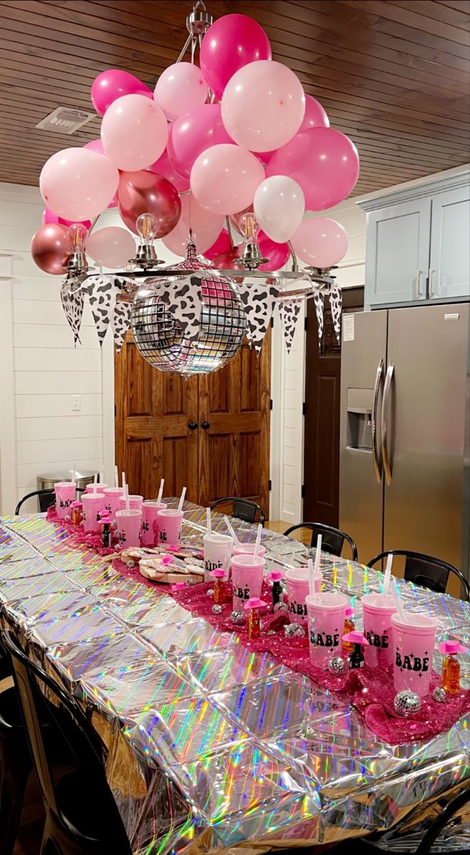 a table with pink candles and balloons on it