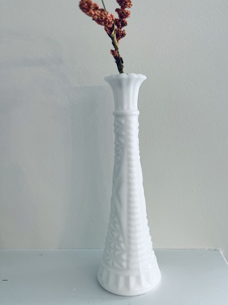 a white vase with some flowers in it