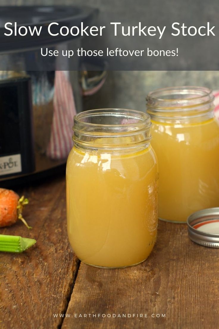 two jars filled with yellow liquid sitting on top of a wooden table next to an open slow cooker