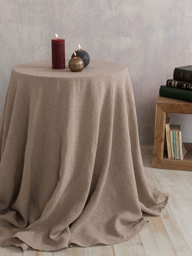 a round table with a candle and some books on it in front of a wall