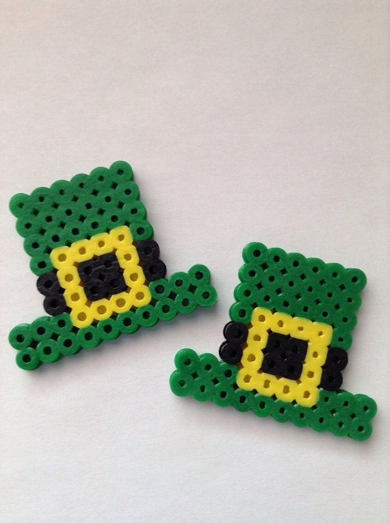 three pieces of green and yellow beaded broochies on a white surface with one piece in the shape of a frog's head