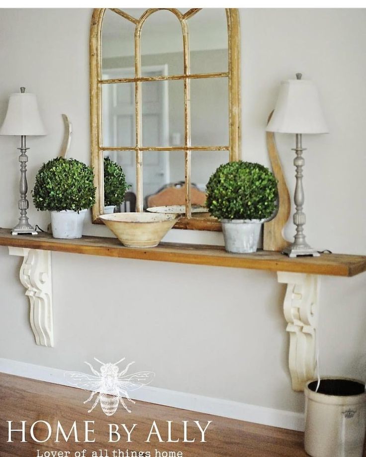 a shelf with potted plants on it and a mirror over the top that says home by ally