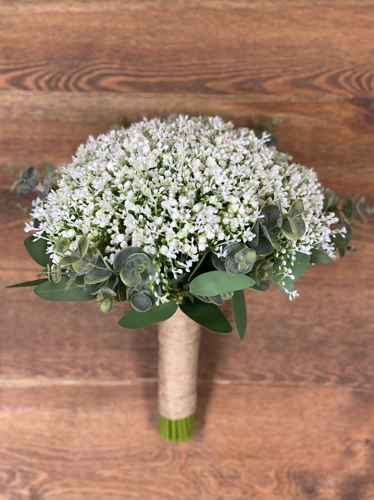 a bridal bouquet with white flowers and greenery on a wooden background, top view