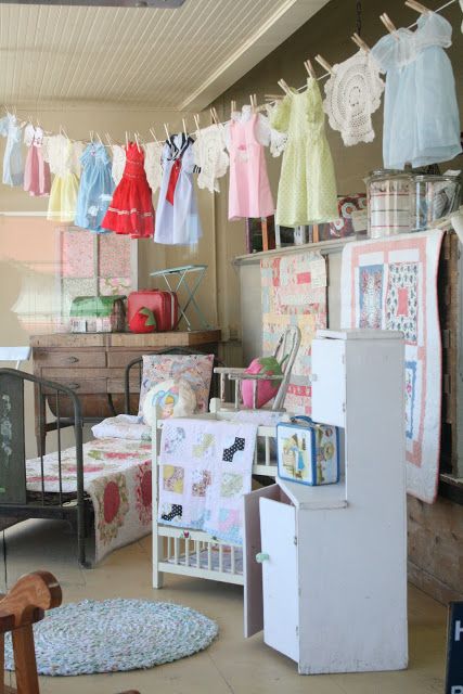 a room filled with lots of clothes hanging from the ceiling and baby cribs