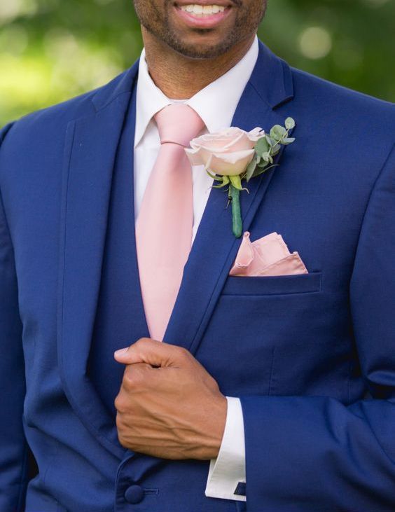 a man in a blue suit with a pink tie and rose boutonniere