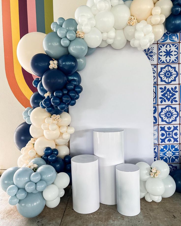 balloons are arranged in the shape of an arch with white pillars and blue vases