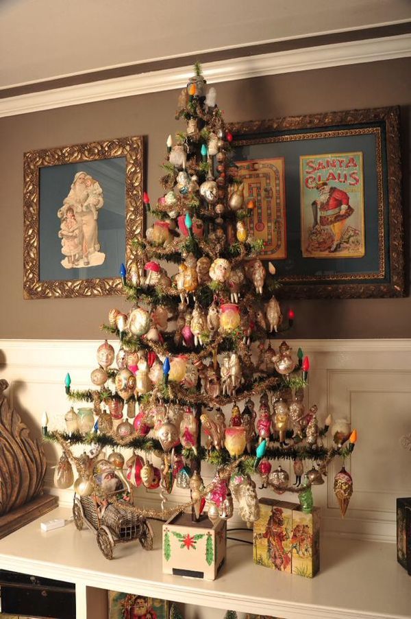 a decorated christmas tree sitting on top of a white shelf next to pictures and ornaments