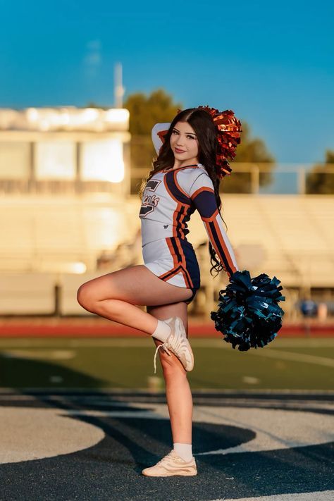 a cheerleader is posing on the field with her pom poms