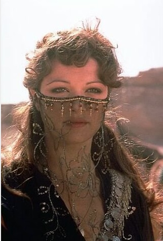 a woman with beads on her face and nose is standing in front of the camera