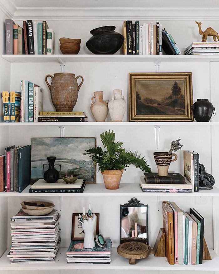 books, vases and other decorative items are on the shelves in this white room