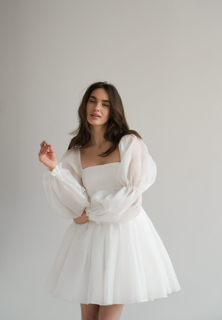 a woman in a white dress posing for the camera with her hands on her hips