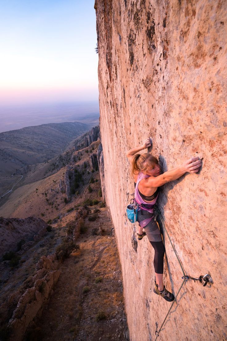 a woman climbing up the side of a mountain