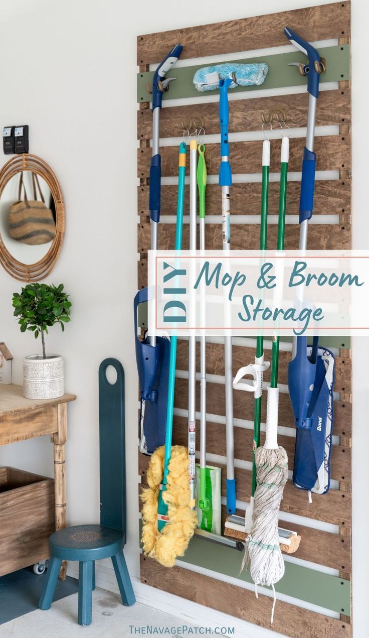 a wooden rack with mop and brooms hanging on the wall next to a blue stool