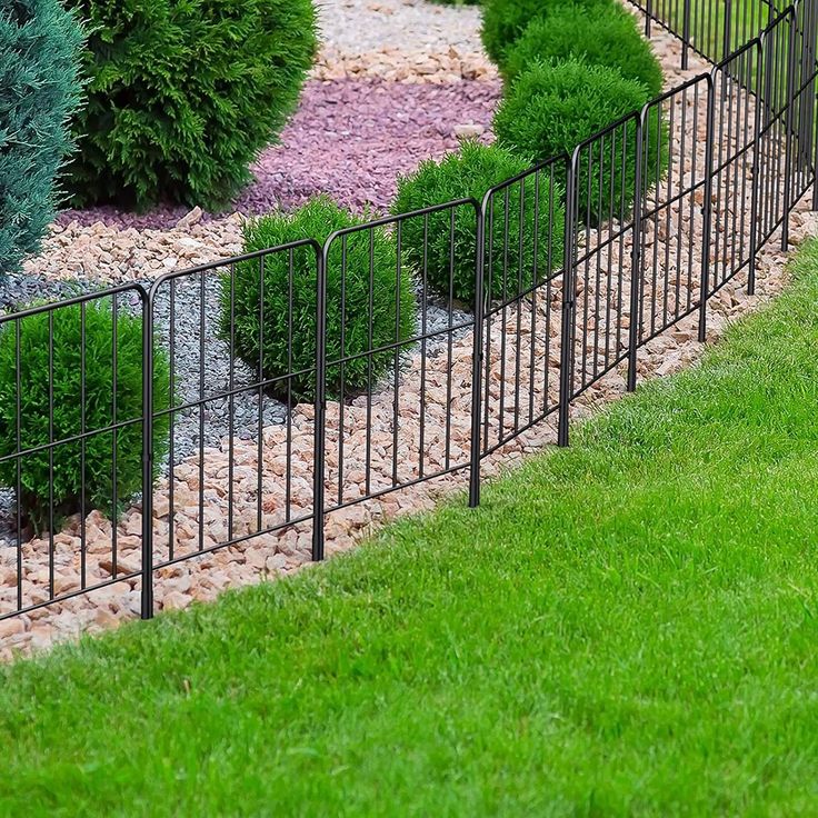 an image of a fenced in area with green grass and bushes on the side