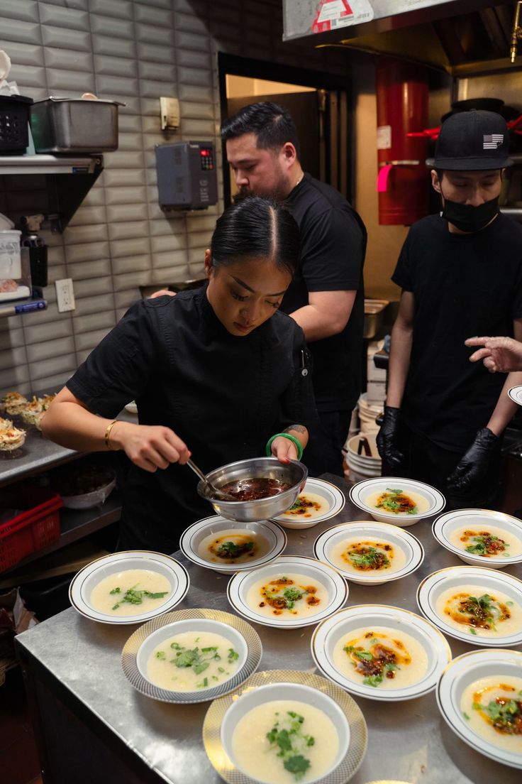 a group of people in a kitchen preparing food on top of pans and plates