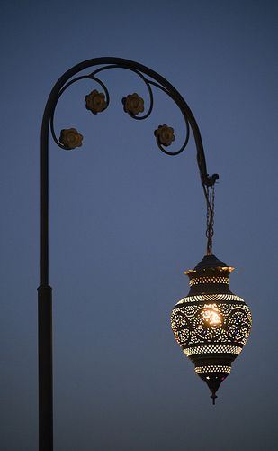 a street light hanging off the side of a pole at night with lights on it