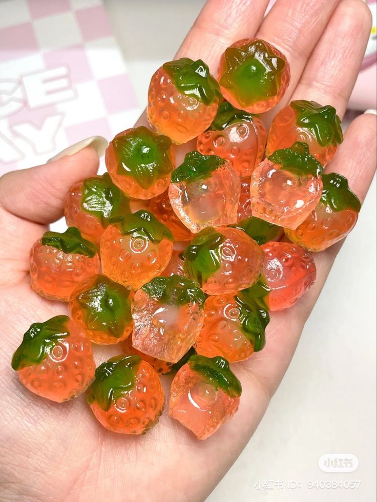 small gummy bears are in the palm of someone's hand with green and orange gummy bears on it