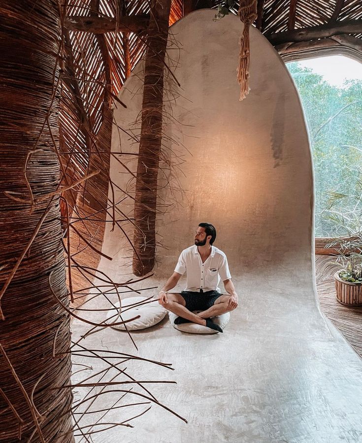 a man is sitting on the floor in front of some trees