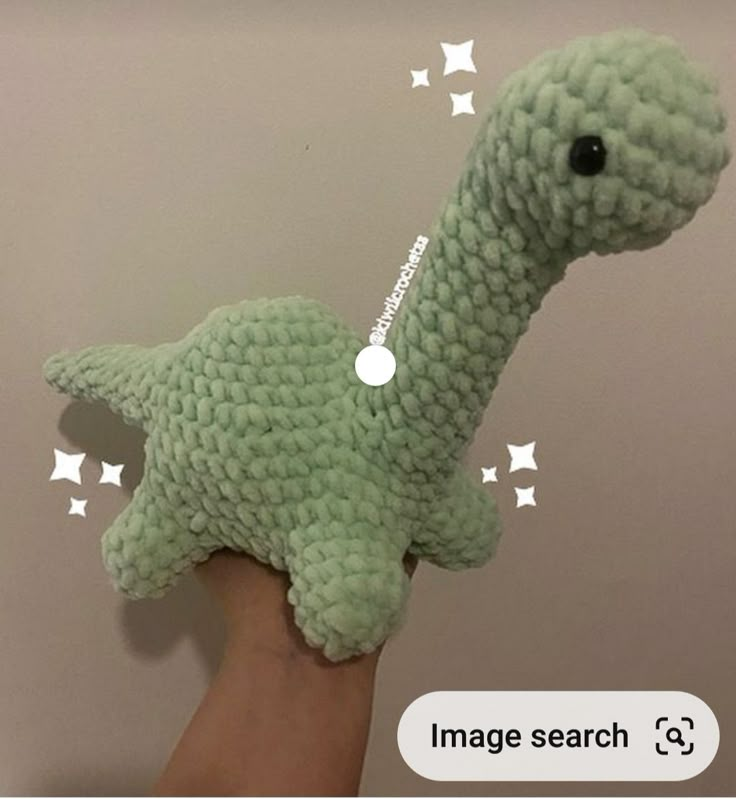 a hand holding a green stuffed animal with white stars on it's side and the text image search below