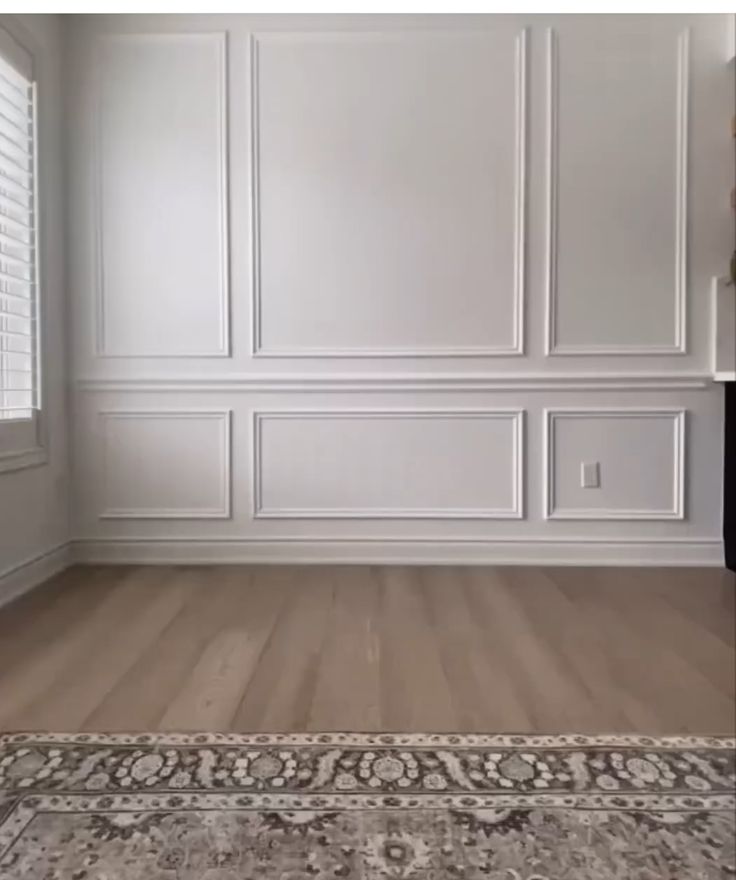 an empty room with white walls and wood floors