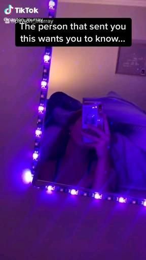 a person taking a selfie in front of a mirror with purple lights on it