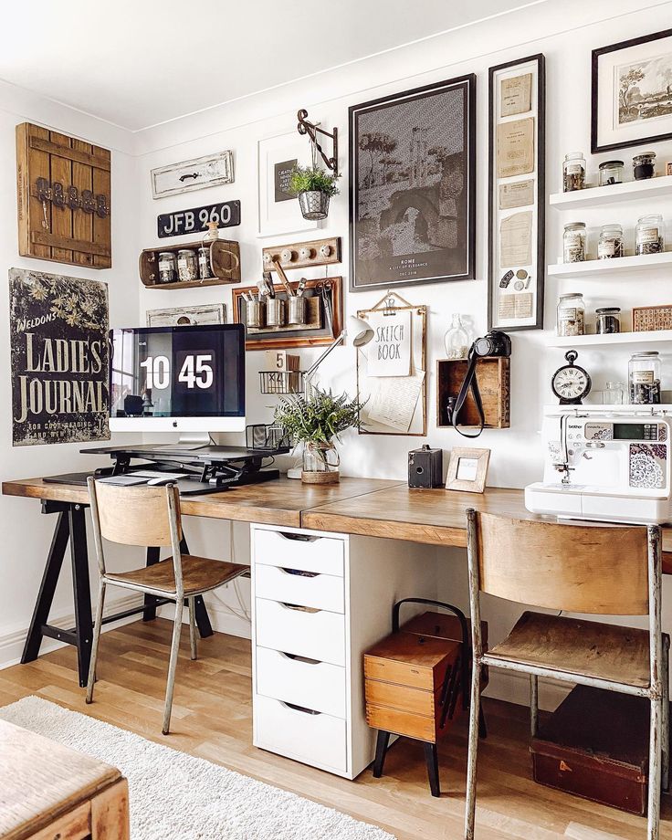 a desk with a computer on top of it in front of some pictures and plants