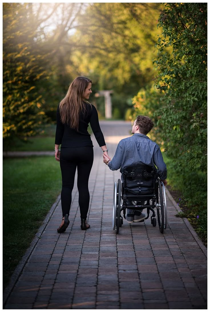 a woman pushing a man in a wheelchair down a path