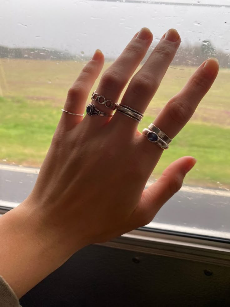 hand with rings painted nails Rings Lesbian Style, Many Rings On Hand Aesthetic, Thumb Rings Aesthetic, Silver Rings Hand, Hands Full Of Rings, Rings Stacking Ideas, Lesbian Rings Hands, Masc Rings For Women, Queer Jewelry Aesthetic