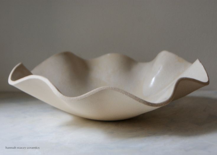 a white bowl sitting on top of a table next to a gray wall and floor