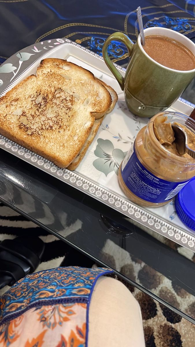 a breakfast tray with toast, coffee and peanut butter on it sits on a table