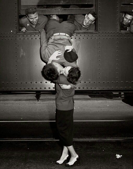 two people are standing in front of a train and one person is holding the other