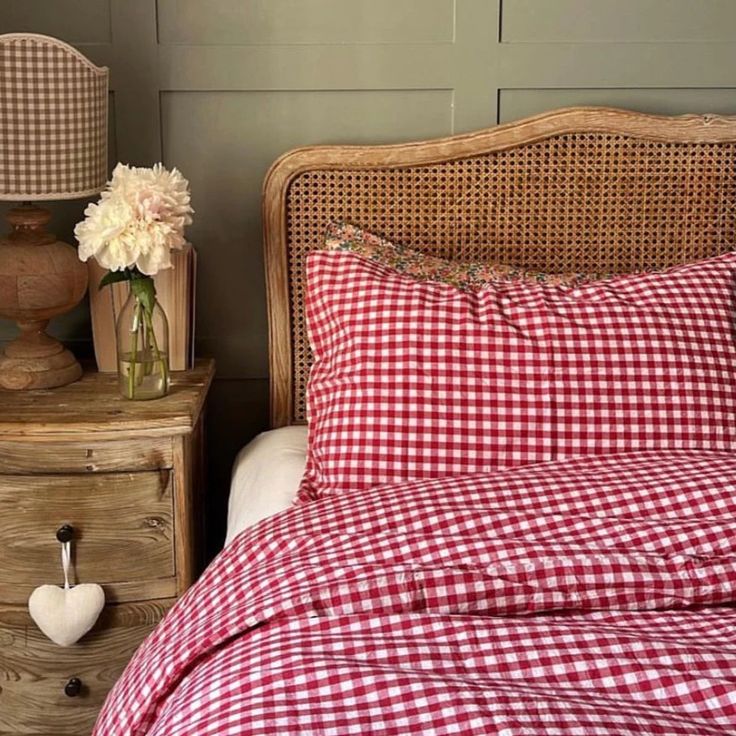 a red and white checkered comforter on a bed next to two nightstands