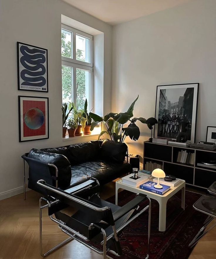 a living room with black leather furniture and potted plants in the window sill