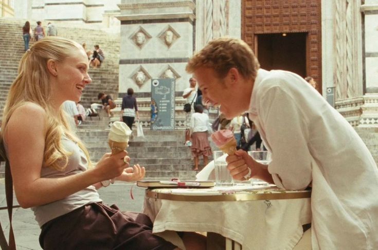 a man and woman sitting at a table eating ice cream