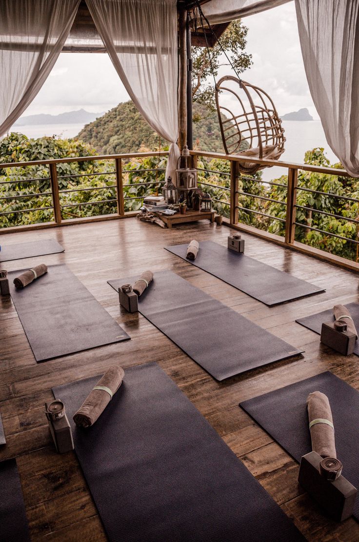 there are many yoga mats on the floor in front of a large window with sheer curtains