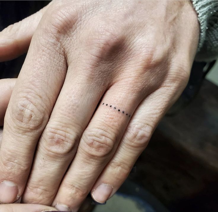 two people with wedding rings on their fingers, one holding the other's hand