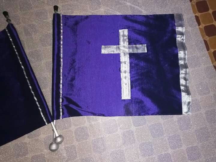 a purple and white flag with a silver cross on it next to two spoons