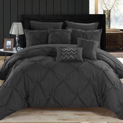 a bed with black comforter and pillows