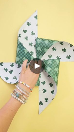 a person is holding a pinwheel made out of paper and shamrocks on it