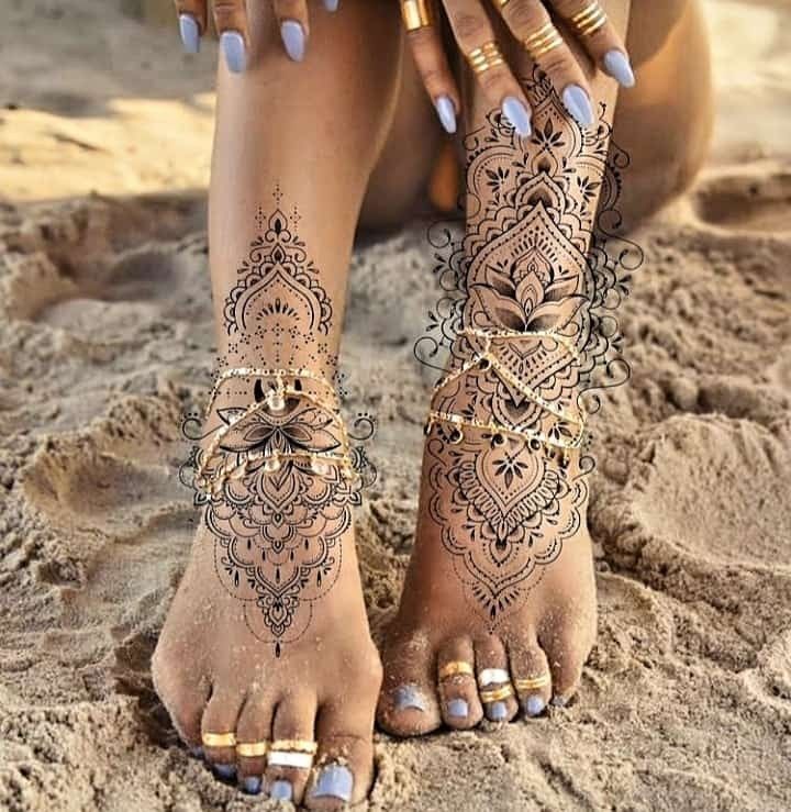 a woman's feet with henna tattoos on them