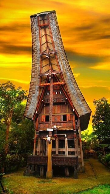 a tall wooden structure sitting in the middle of a lush green field under a cloudy sky