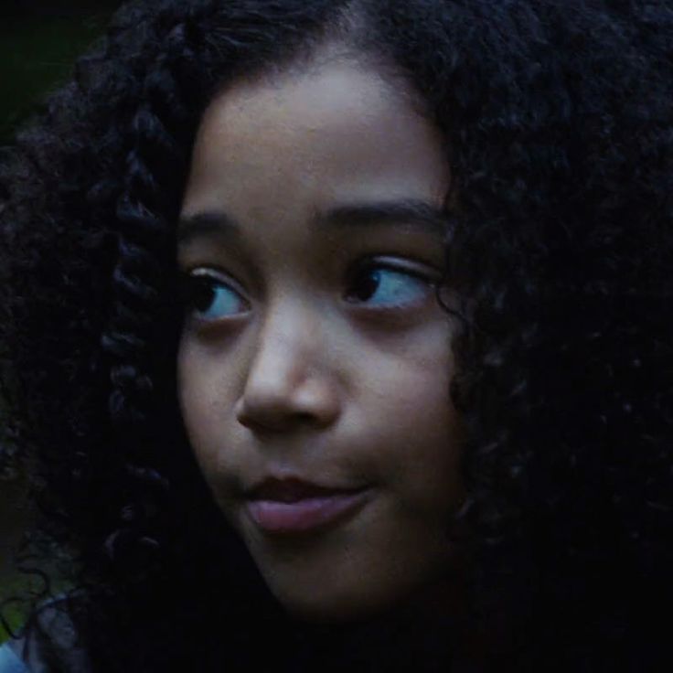 a close up of a person with curly hair looking down at her cell phone screen