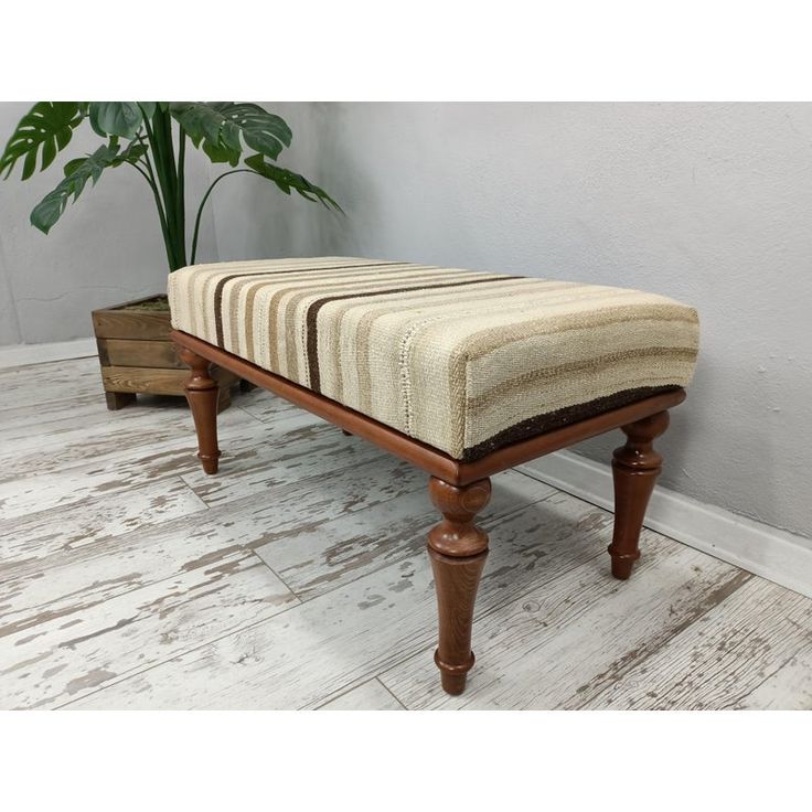 a bench made out of wood with a striped seat cushion on the bottom and legs