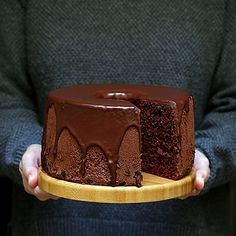 a person holding a plate with a chocolate cake on it