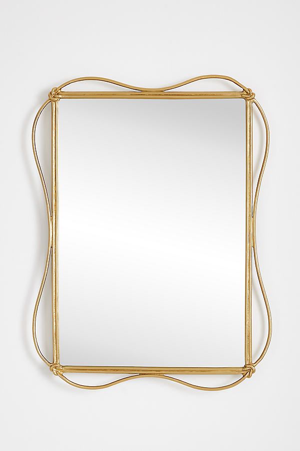 a gold framed mirror on a white wall with an intricate design around the edges and sides