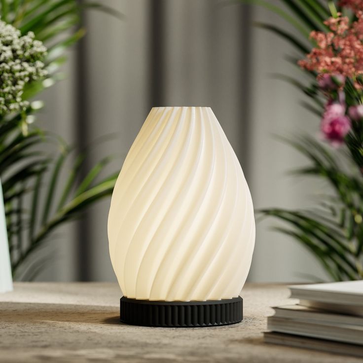 a white vase sitting on top of a table next to some plants and flowers in the background