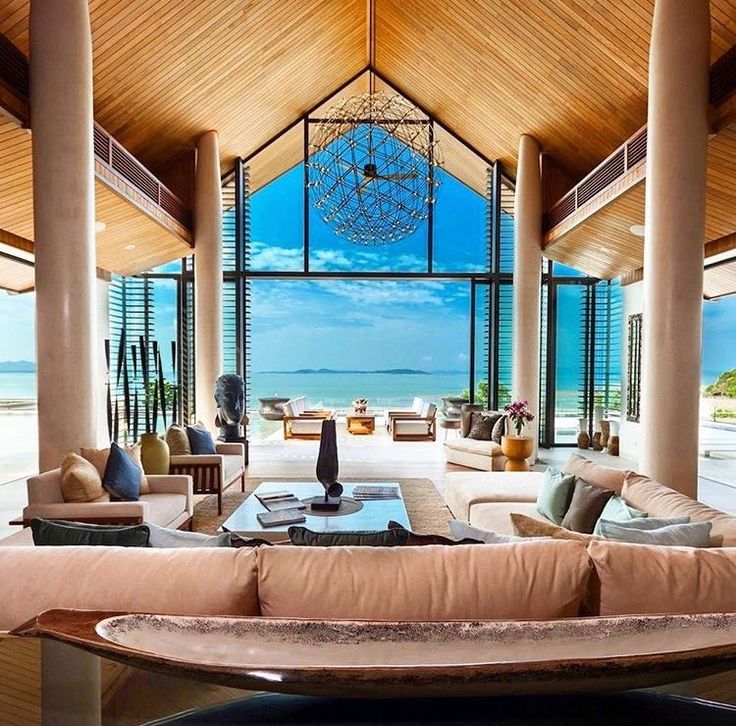 a living room filled with lots of furniture next to large windows overlooking the ocean and beach