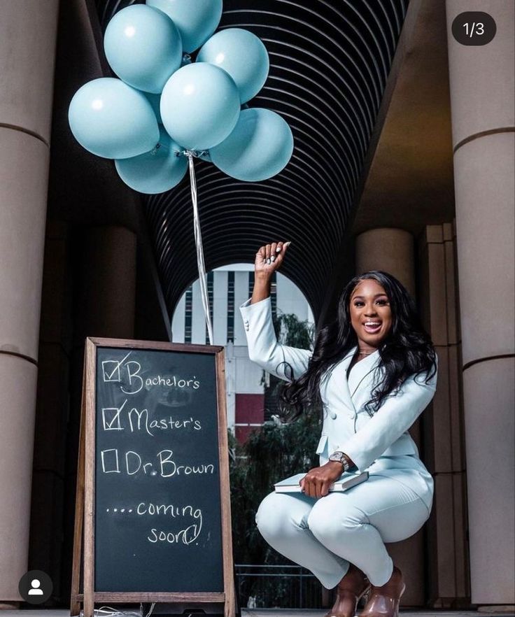 a woman kneeling down next to a sign and balloons